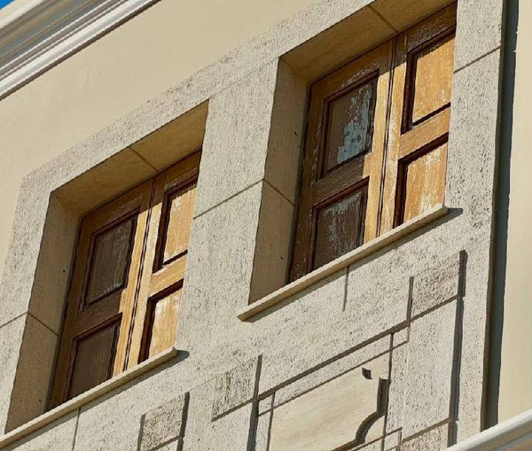 Close-up of a building facade with decorative stone work and wooden windows.